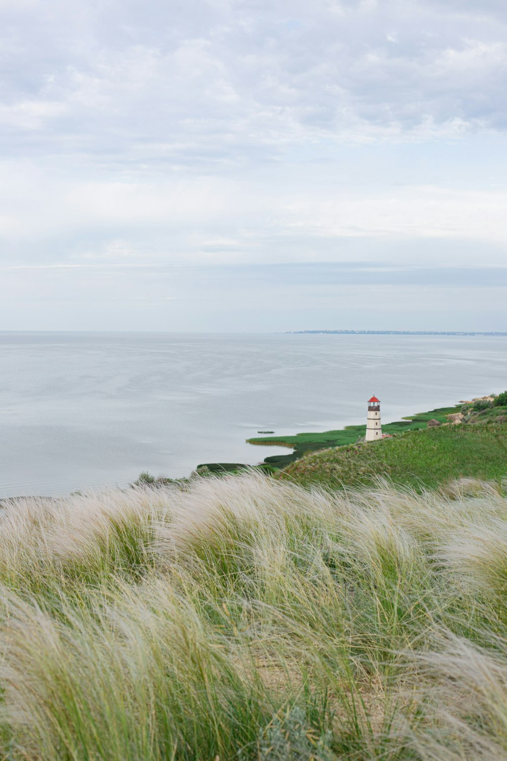 a lighthouse on a grassy hill overlooking the ocean