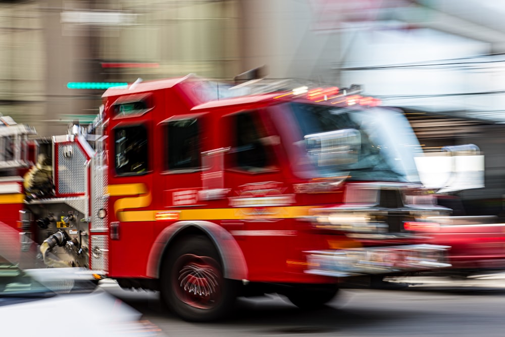 a red fire truck driving down a street next to a tall building