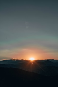 A serene sunrise over a mountain range symbolizing the harmony of science and faith.