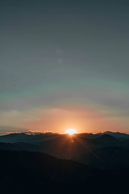 A serene sunrise over a misty mountain range with soft pastel hues painting the sky.