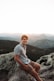 a man sitting on top of a large rock