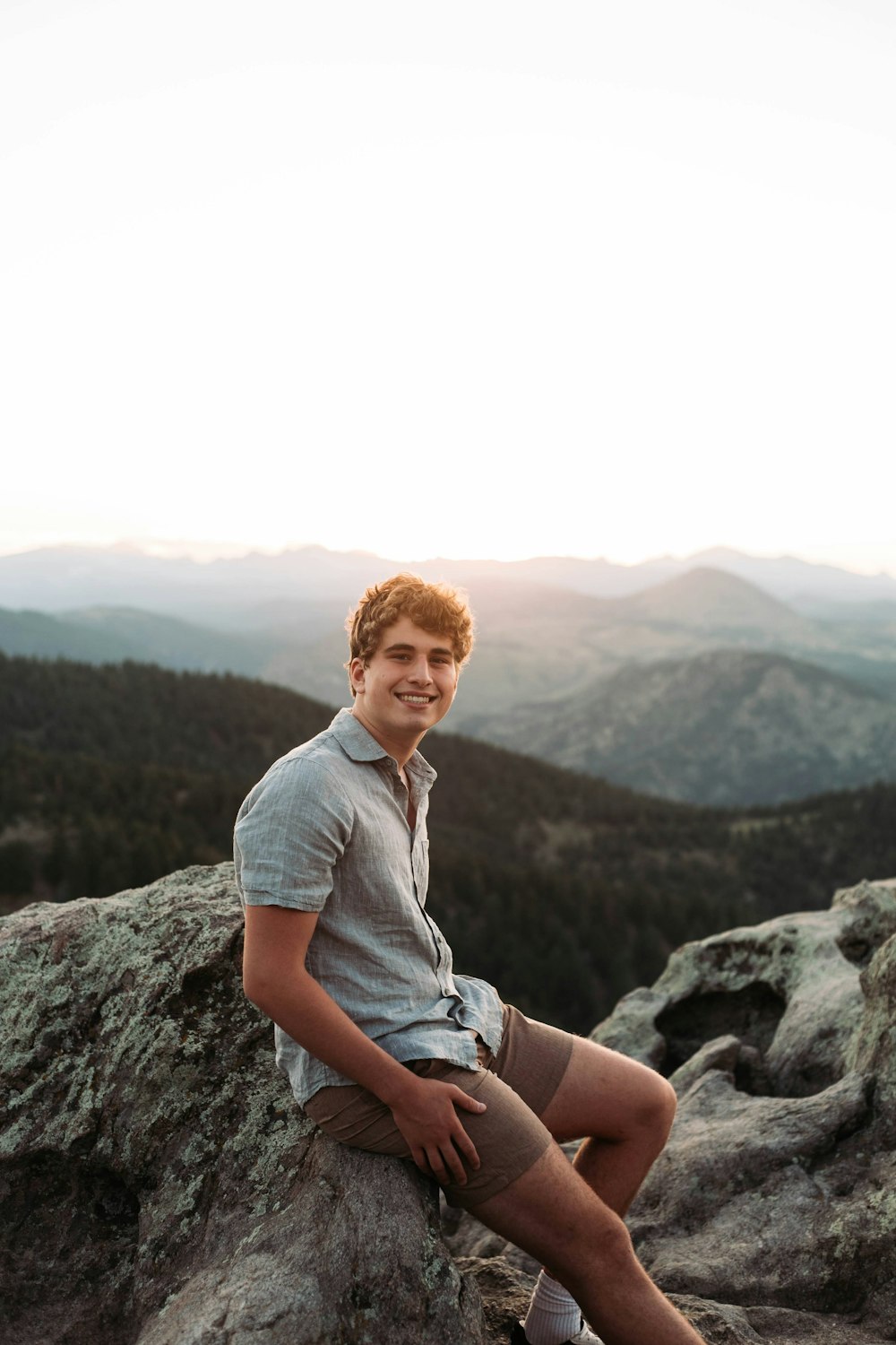 a man sitting on top of a large rock