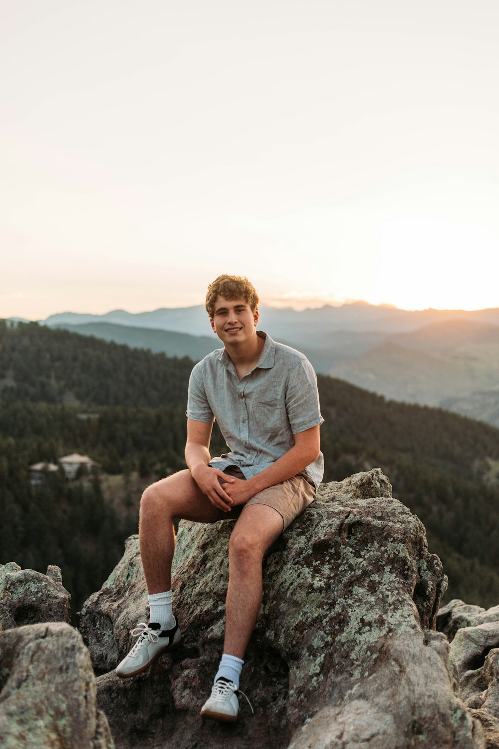 a man sitting on top of a large rock