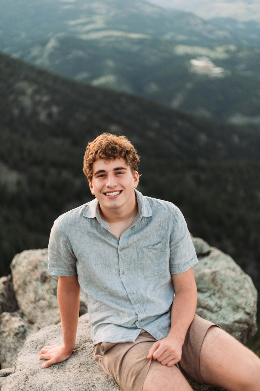 a young man sitting on top of a rock