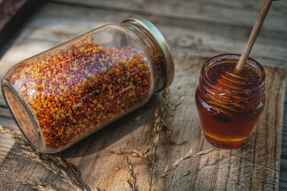 a jar filled with some kind of food next to a glass of liquid