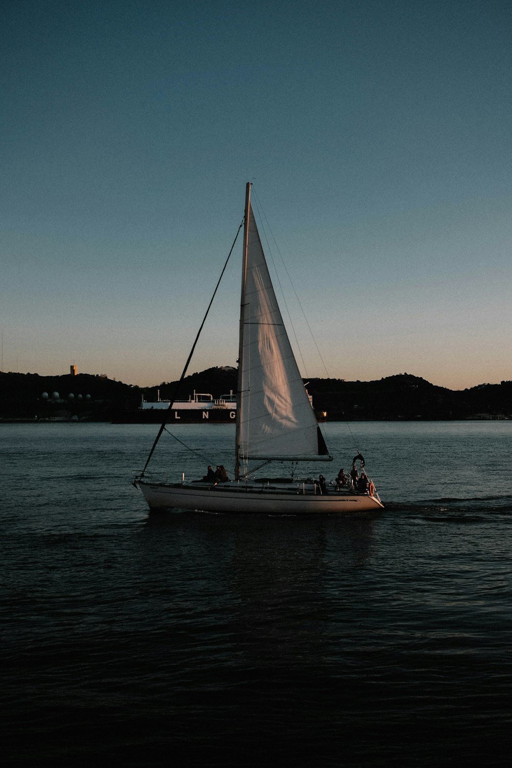 a sailboat with a white sail on a body of water