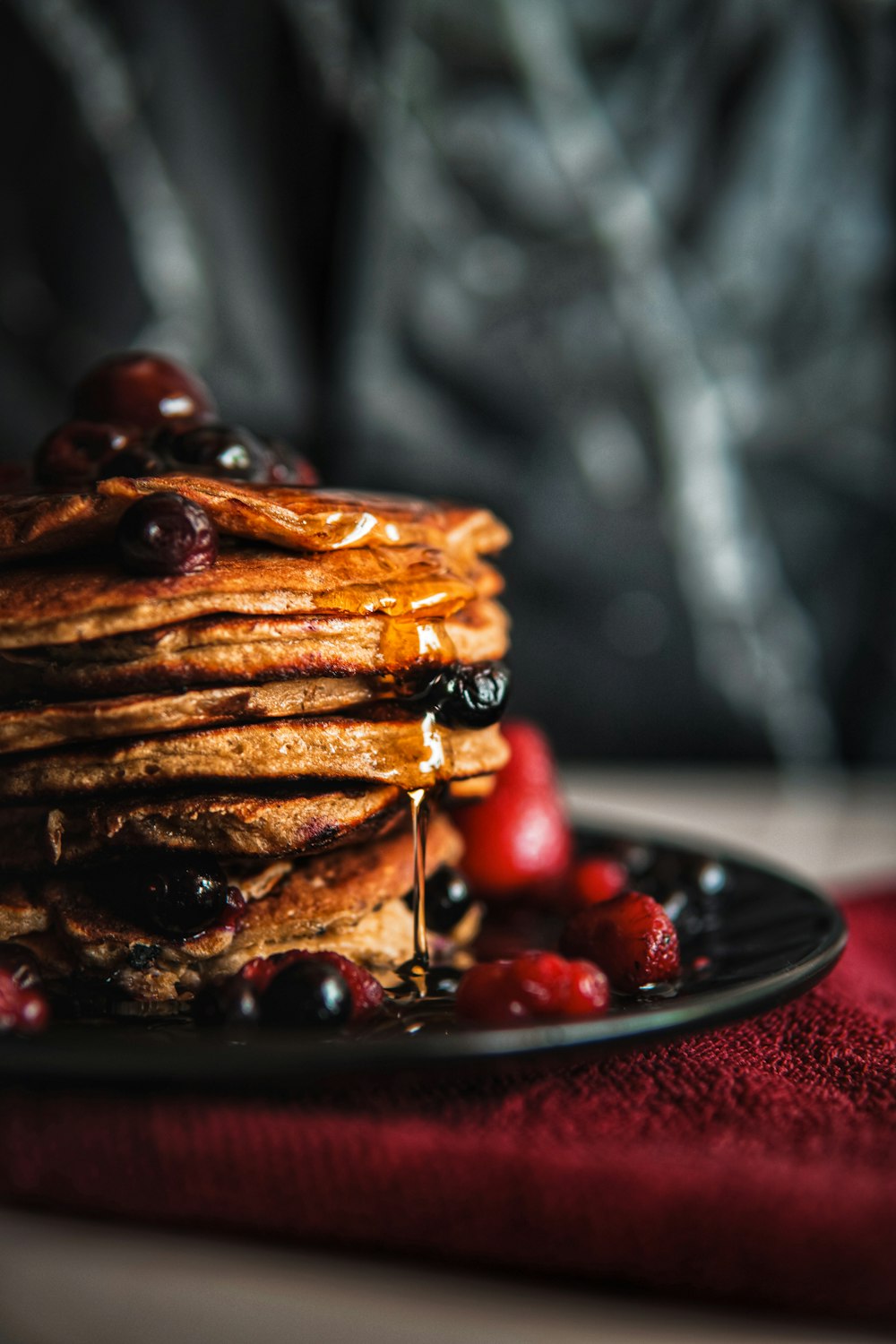 a stack of pancakes with syrup and berries on a plate