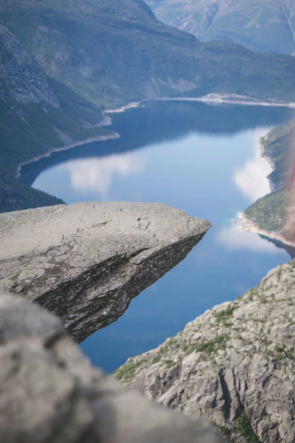 a man standing on top of a cliff next to a lake