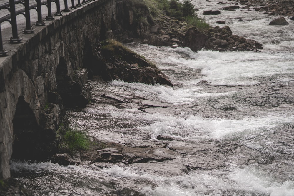 a bridge over a river next to a stone wall