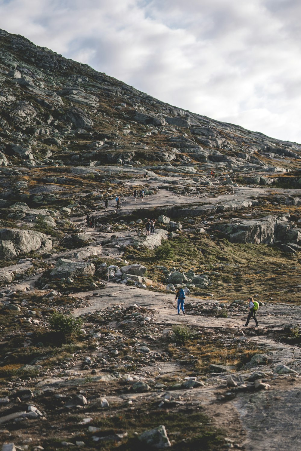 um grupo de pessoas caminhando por uma colina rochosa