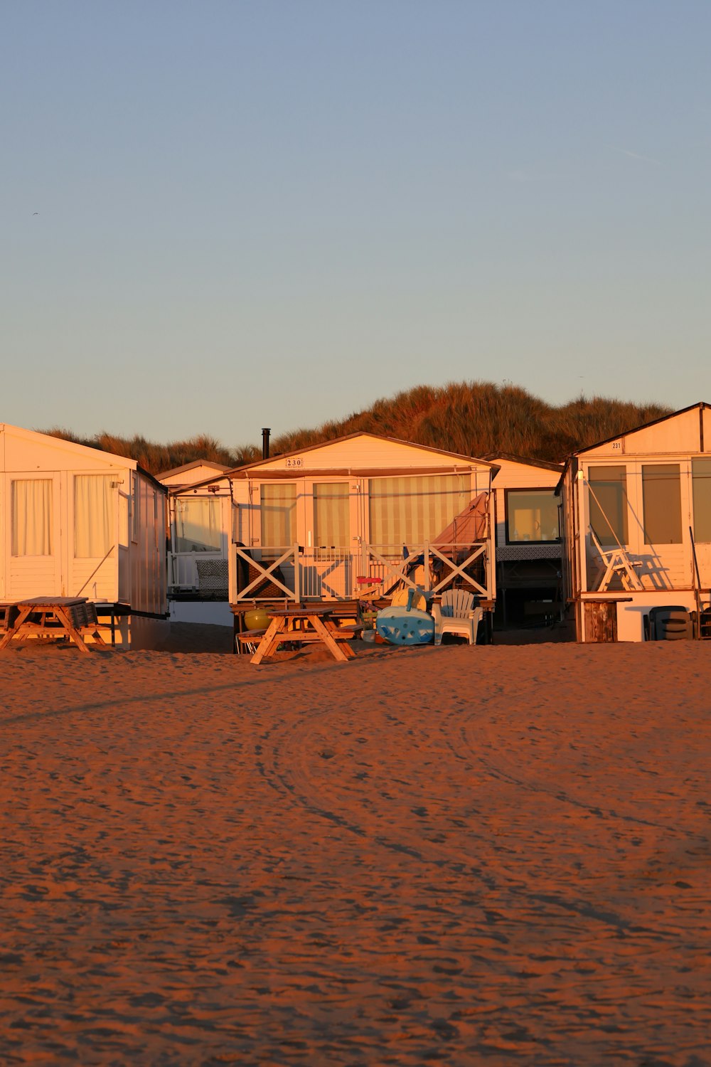 une rangée de cabanes de plage assises au sommet d’une plage de sable