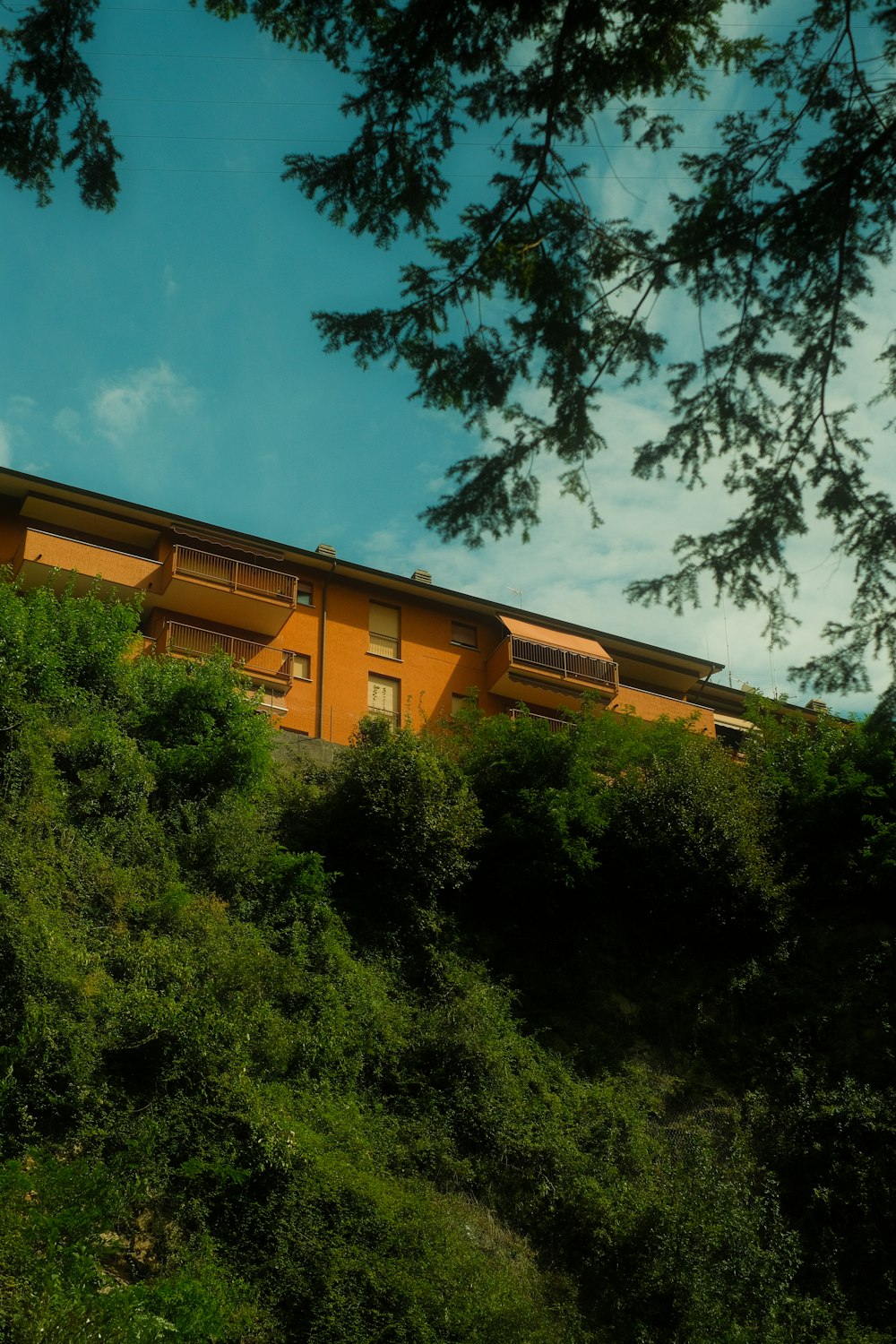 a yellow building sitting on top of a lush green hillside