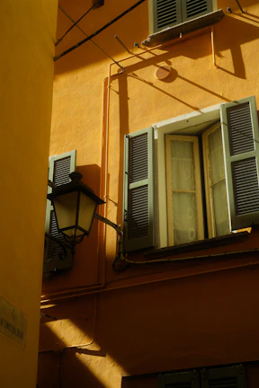 Close-up of a smooth, freshly painted black and gold exterior wall under bright sunlight.
