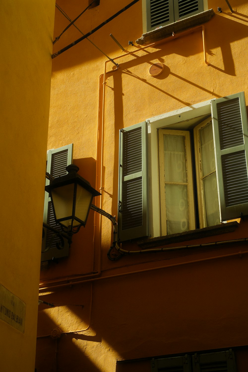 a yellow building with shutters and a lamp
