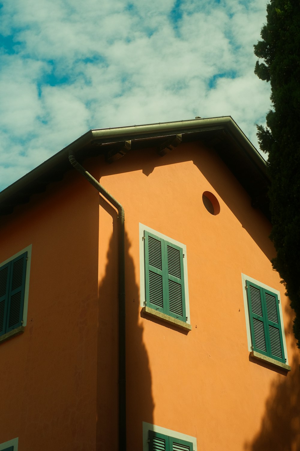 an orange building with green shutters and a tree
