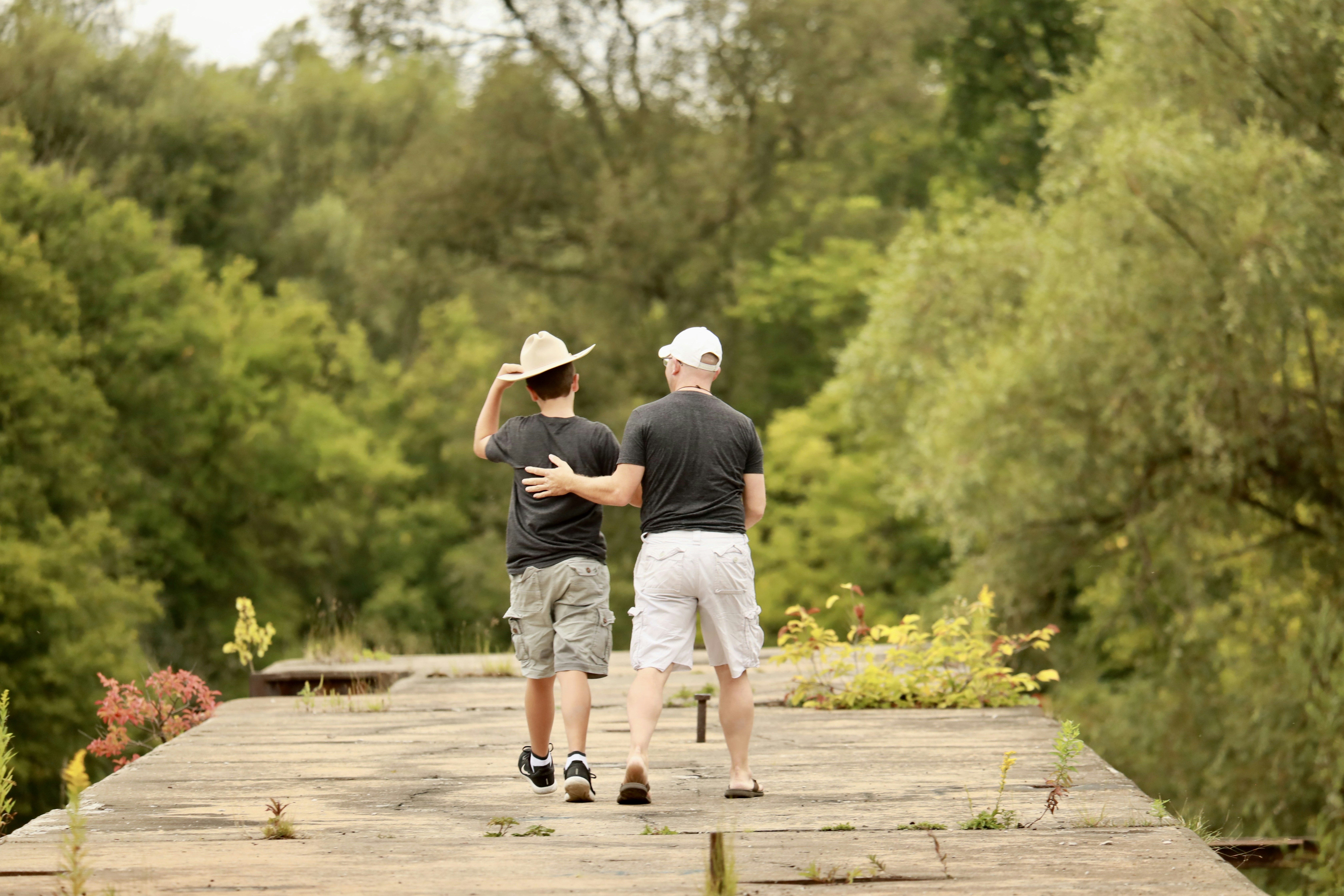 A couple of men standing on top of a wooden bridge photo – Free Nature ...