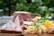 A platter of charcuterie and fresh greens is arranged on a wooden surface. Slices of cured meat and pâté are paired with what appears to be a side of toast, arugula, and sliced tomatoes. There are also some pickled items and a portion of shredded cheese or pasta.