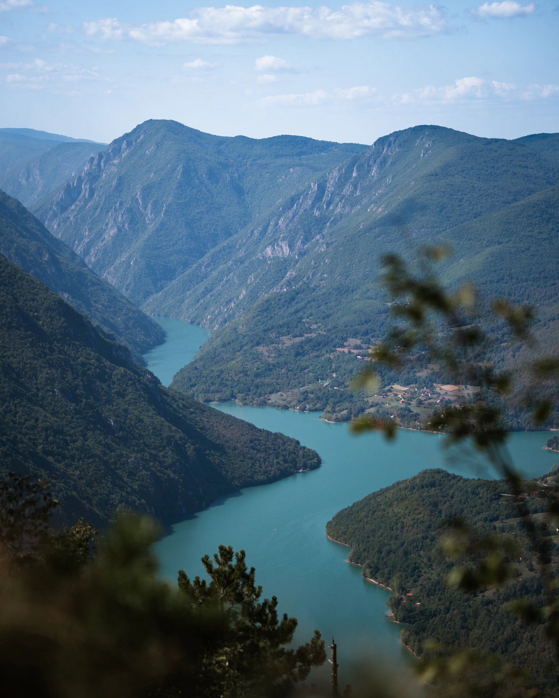 A serene turquoise river winding through lush green valleys dotted with traditional Tibetan villages.