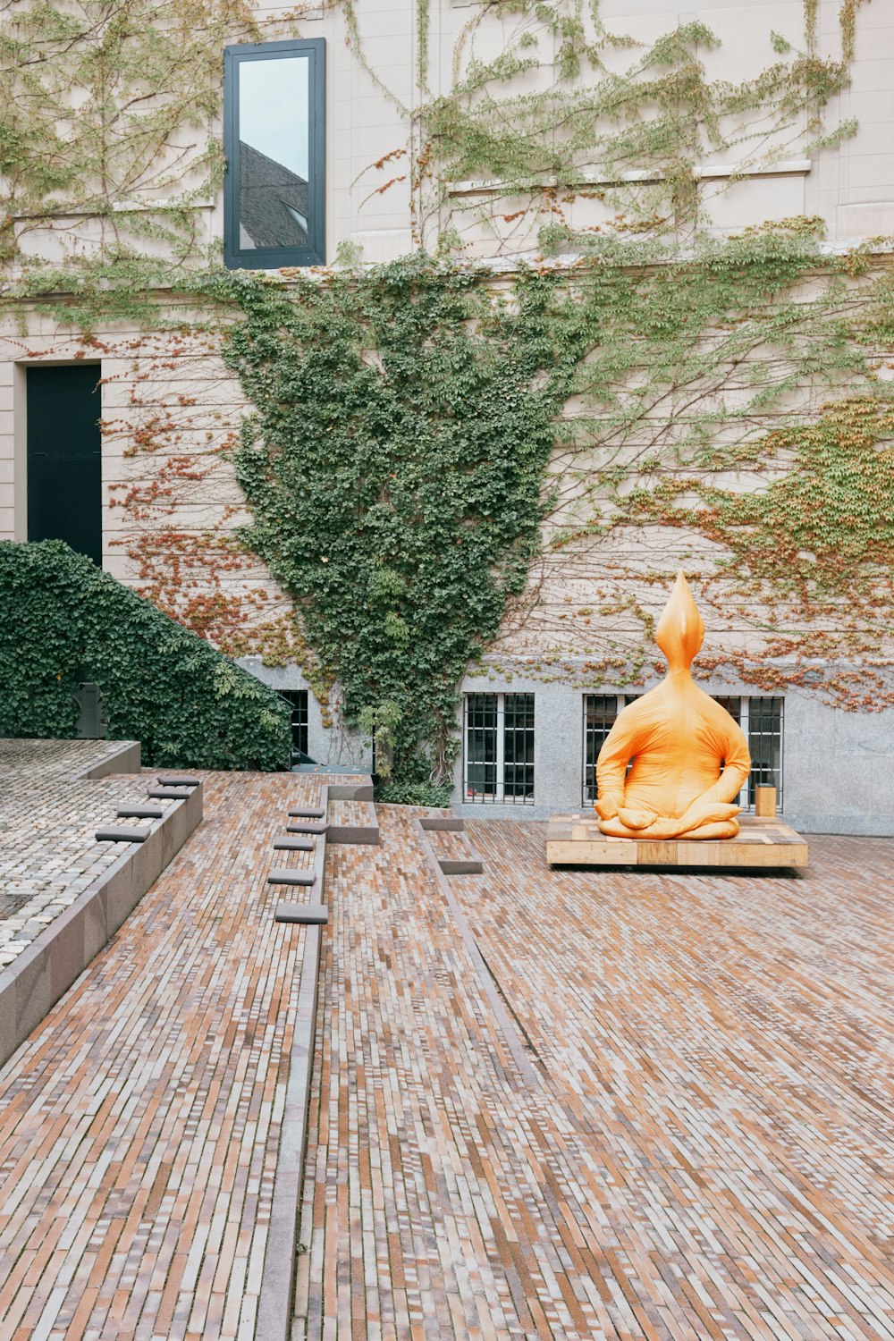 a statue of a person sitting on a bench in front of a building