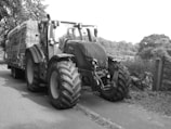 A heavy-duty truck loaded with agricultural equipment on a rural road.