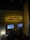 A bar and grill setting features a prominently lit sign reading 'Red Embers Bar & Grill' with a flame design. Below the sign, two mounted televisions display different sports events. The setting includes dim lighting with a modern interior, featuring stone accents and seating areas.