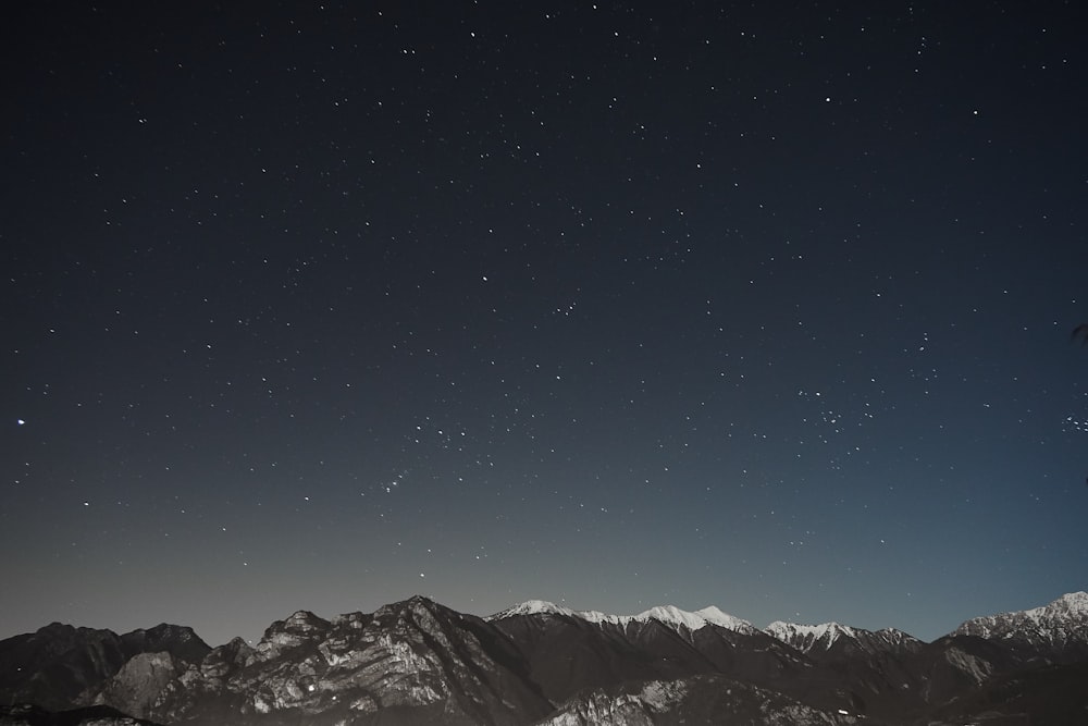 the night sky with stars above a mountain range