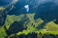 A group of friends paragliding over lush green valleys with the sun casting golden hues.