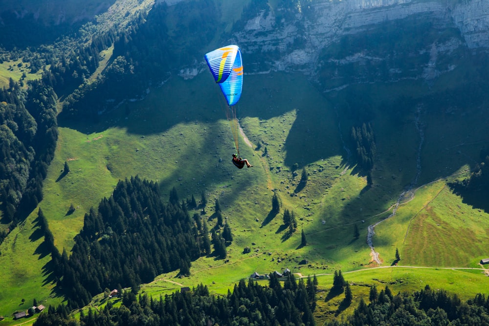 a couple of parachutes flying over a lush green hillside