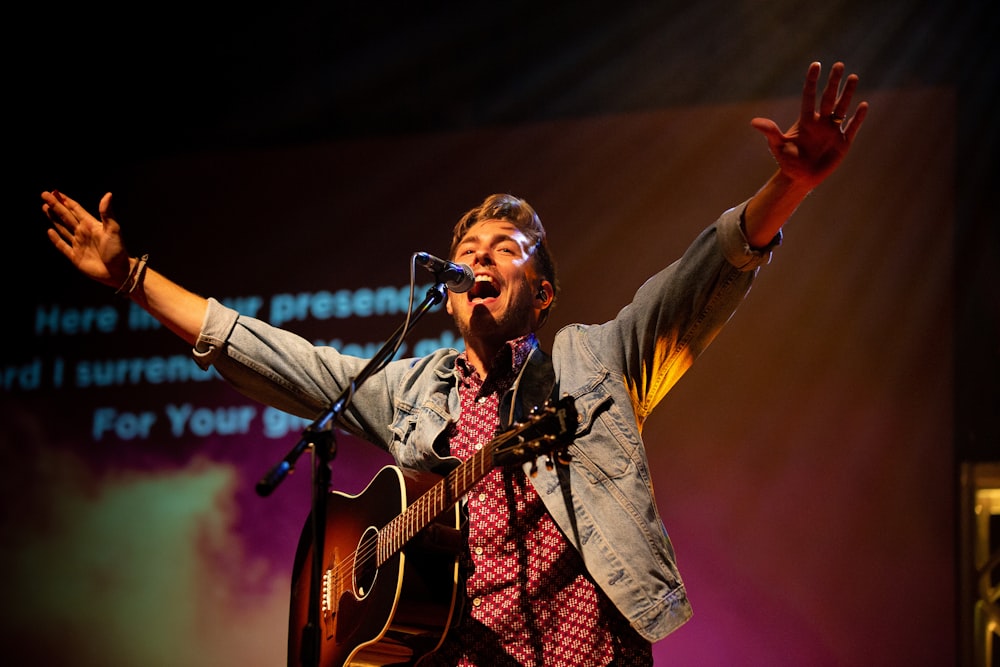 a man singing into a microphone while holding a guitar