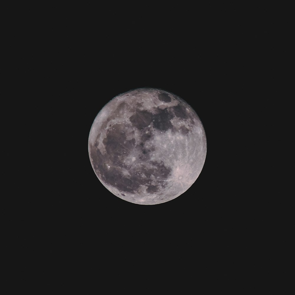 uma lua cheia é vista no céu escuro