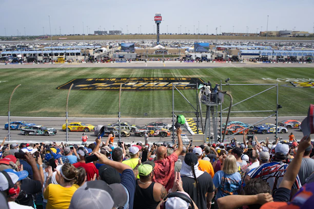 A thrilling endurance race car speeding on a sunlit racetrack with cheering fans in the background.