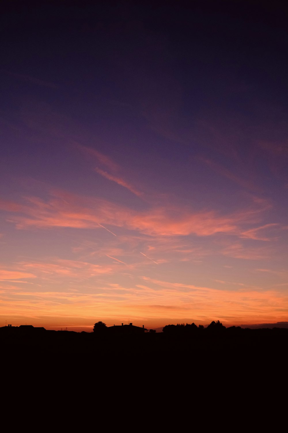 a plane flying in the sky at sunset