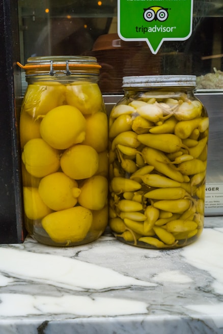 Fresh lemon pickles in traditional glass containers with visible mustard seeds
