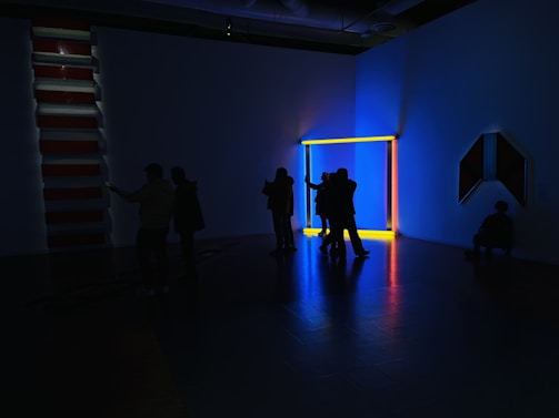 A dimly lit installation showing shadows of intertwined human and machine silhouettes.