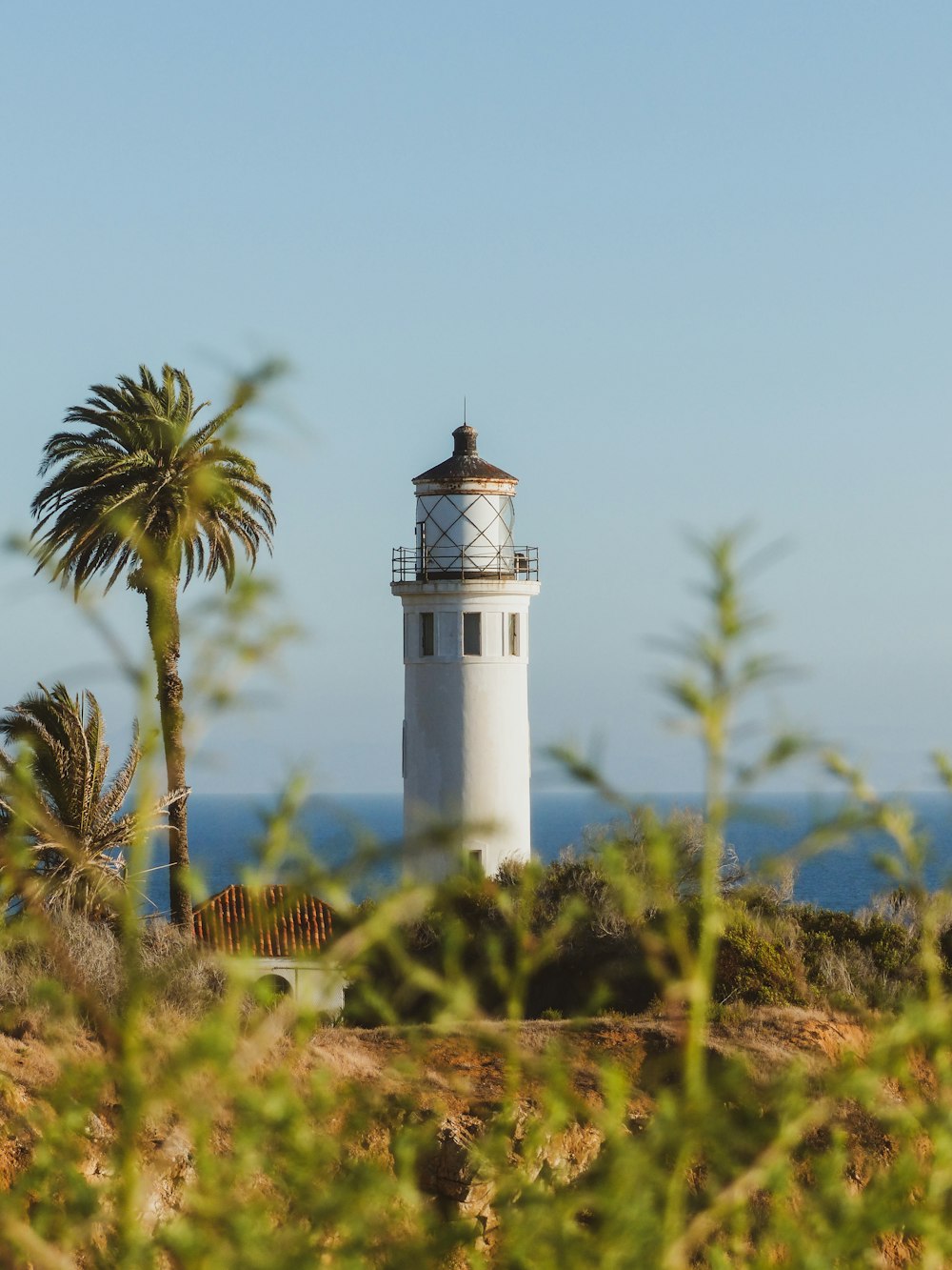 a white light house sitting on top of a hill