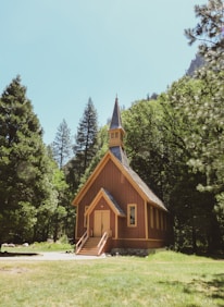 A peaceful sunrise casting golden light over a quiet chapel surrounded by trees.