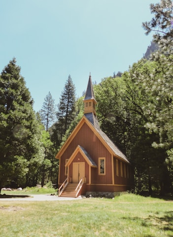 A peaceful sunrise casting golden light over a quiet chapel surrounded by trees.