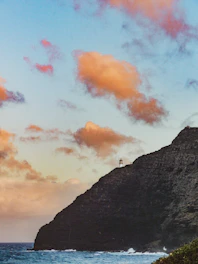 Dramatic view of Cap Spartel lighthouse where the Atlantic Ocean meets the Mediterranean Sea under a bright blue sky.
