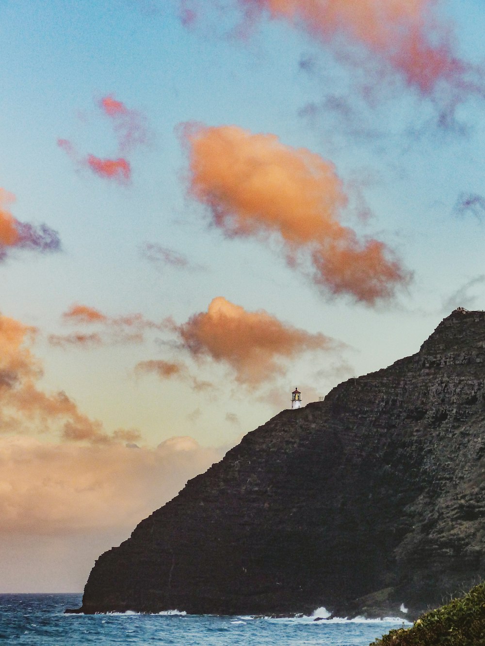 a person standing on top of a mountain next to the ocean