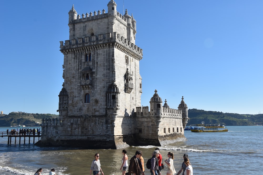 a group of people walking on a beach next to a tall tower