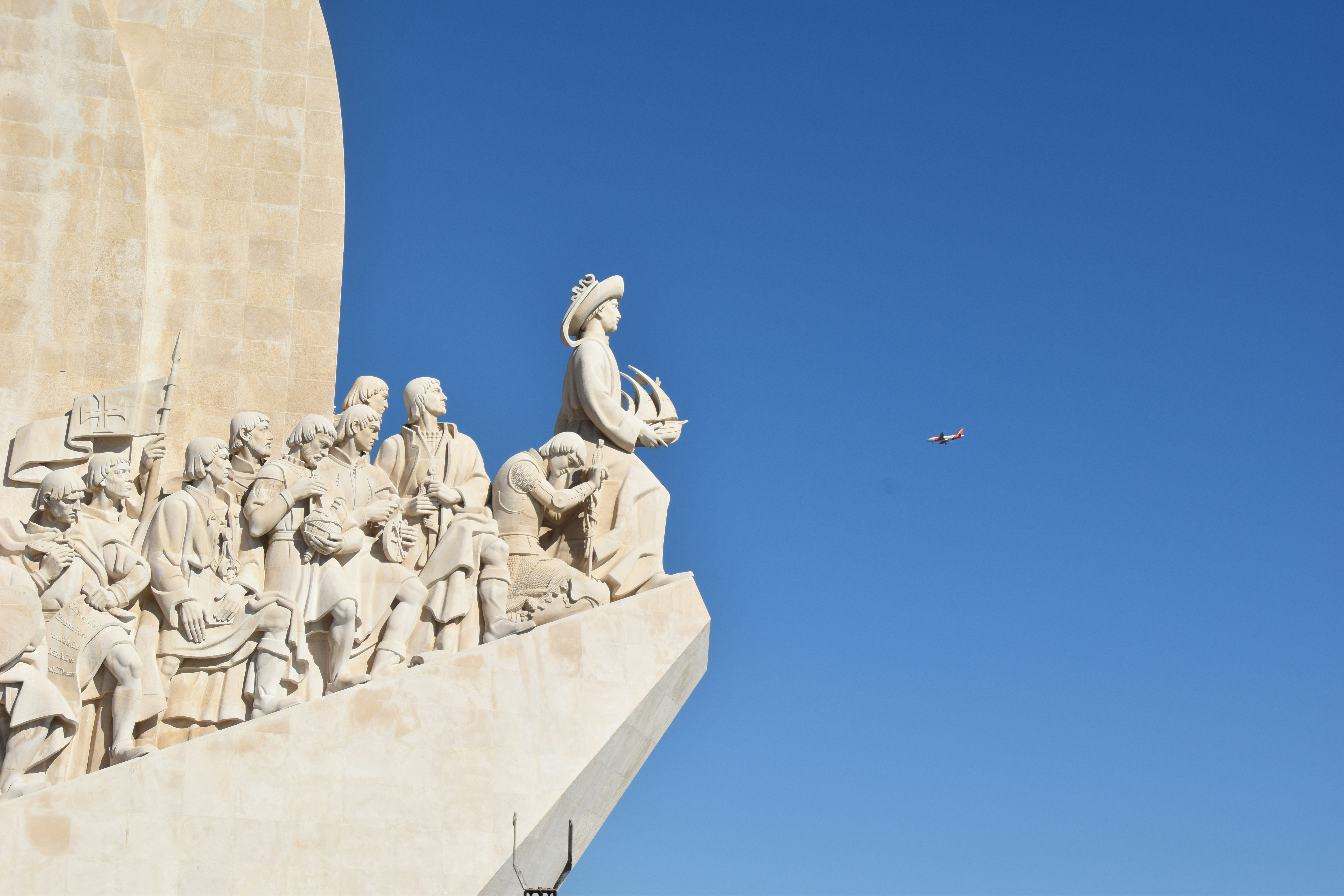a plane flying over a statue of a group of people