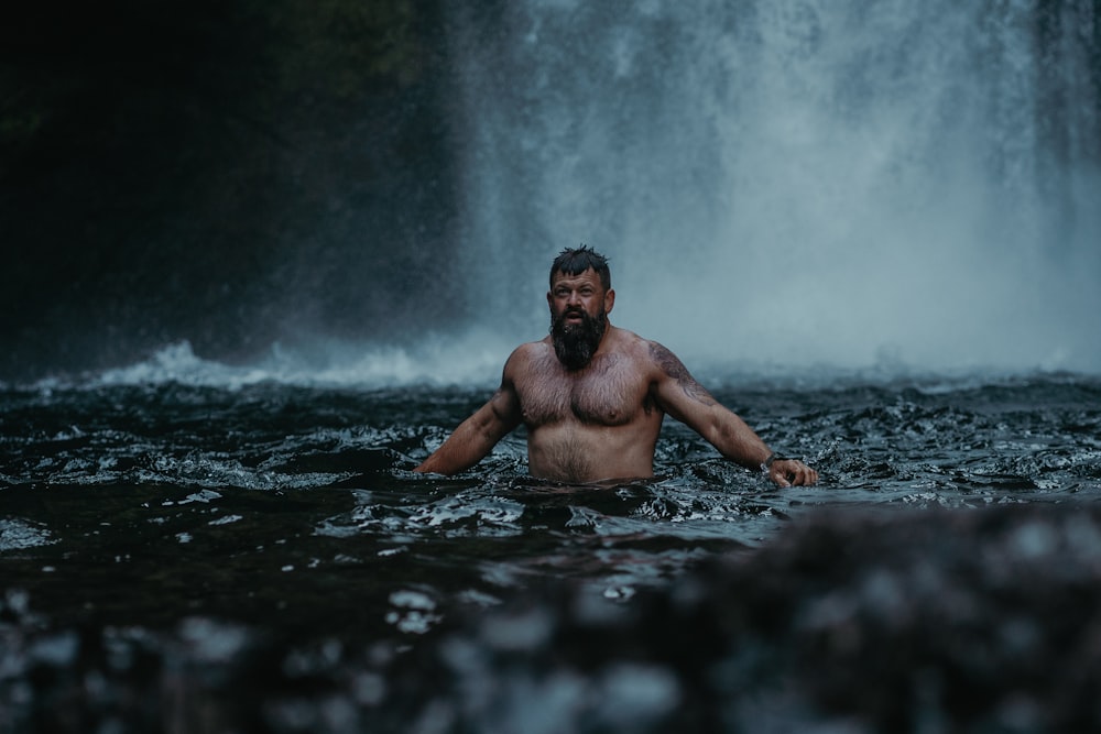 Ein Mann, der im Wasser vor einem Wasserfall steht