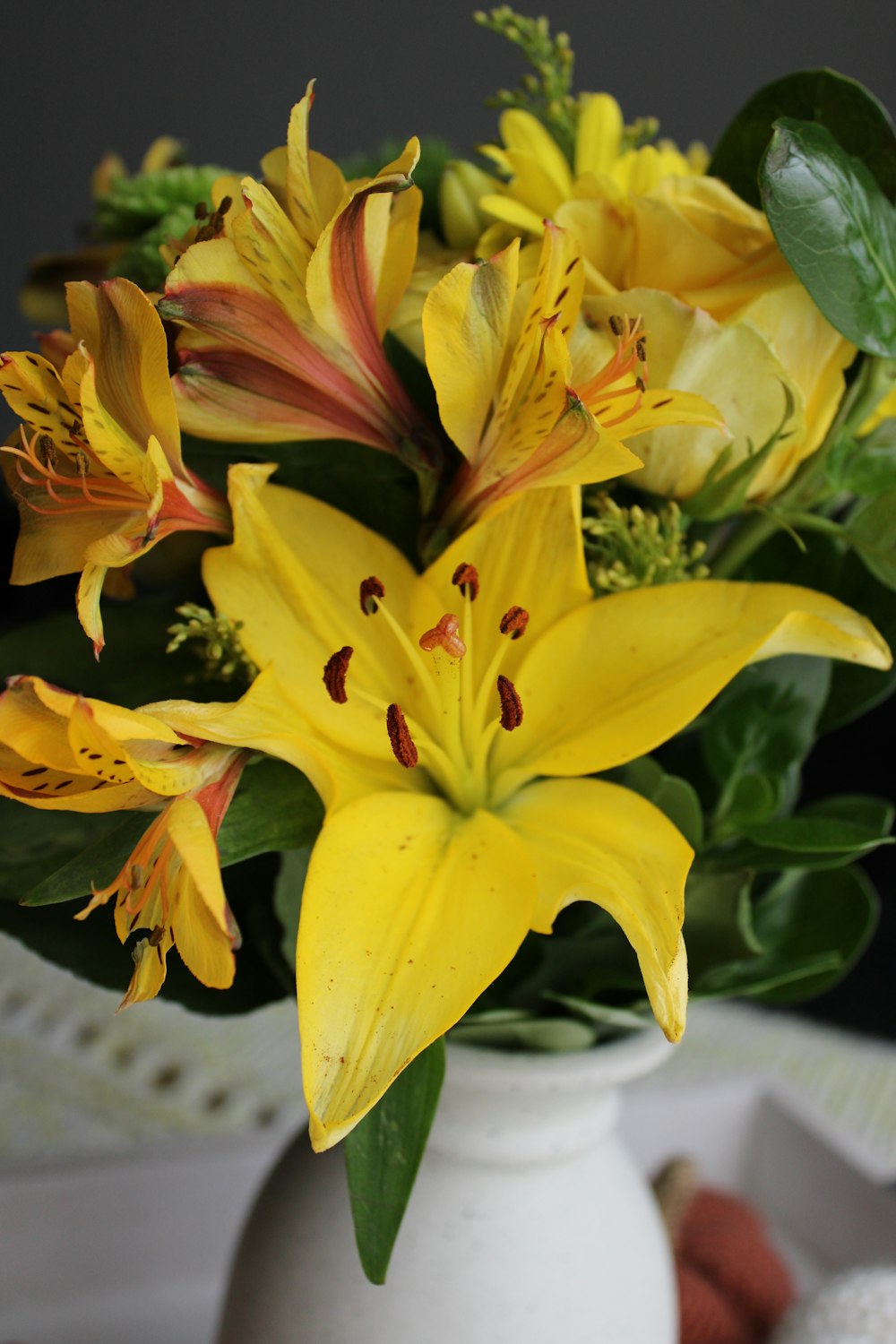 a white vase filled with yellow flowers on top of a table