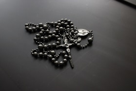 a rosary is laying on a black surface