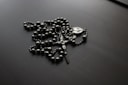 a rosary is laying on a black surface