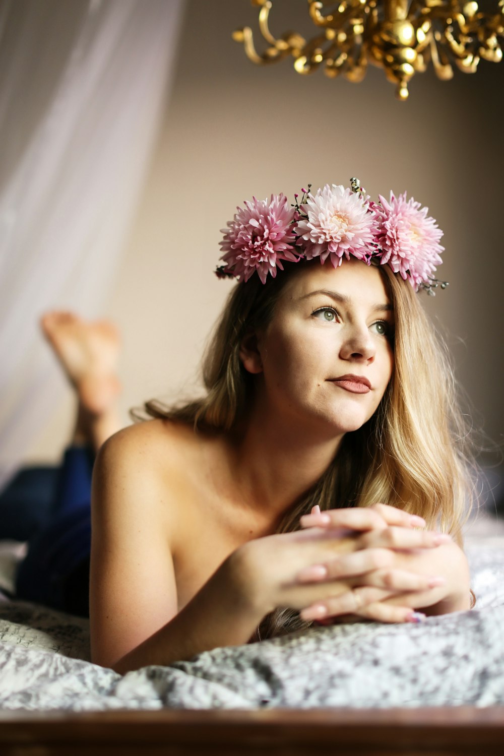 a woman laying on a bed wearing a flower crown