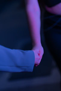 A couple holding hands surrounded by soft white and violet light symbolizing harmony.