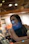 Close-up of a thoughtful woman smiling softly in a cozy, dimly lit room.