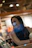 Smiling woman giving a thumbs up in a cozy home setting.