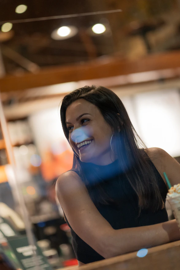 Close-up of a calm, smiling woman sitting comfortably in a modern, cozy psychologist's office.